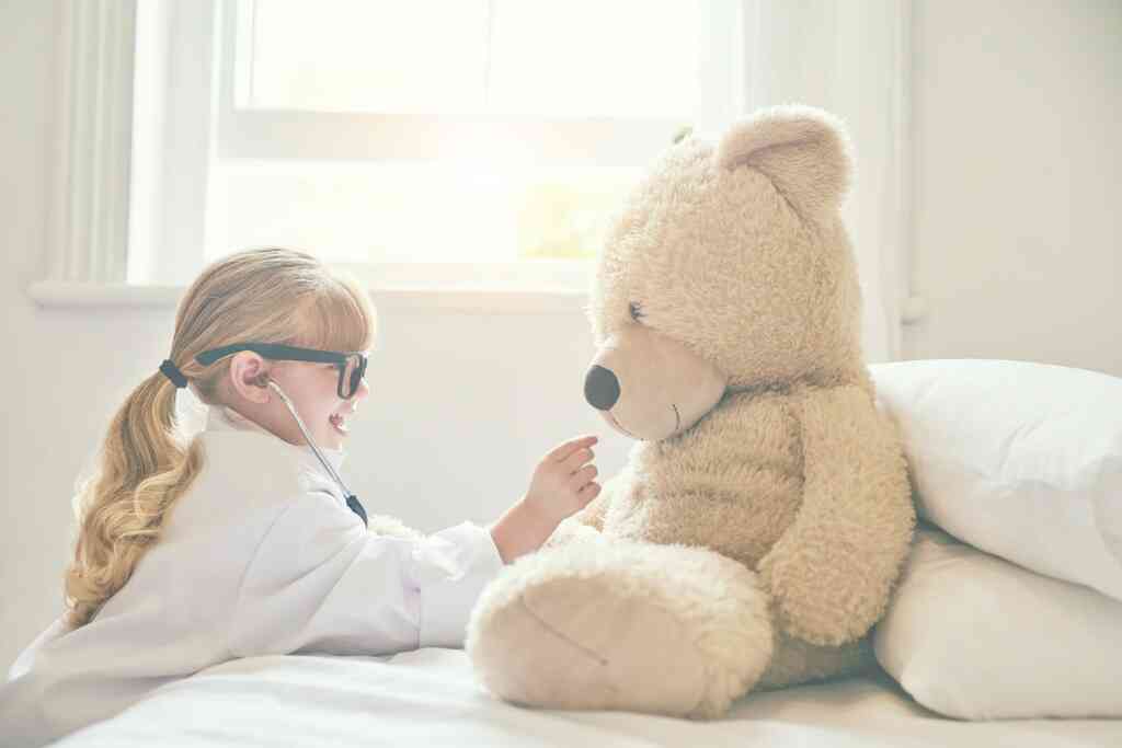 ילדה משחקת ברופא וחולה עם הדובי שלה